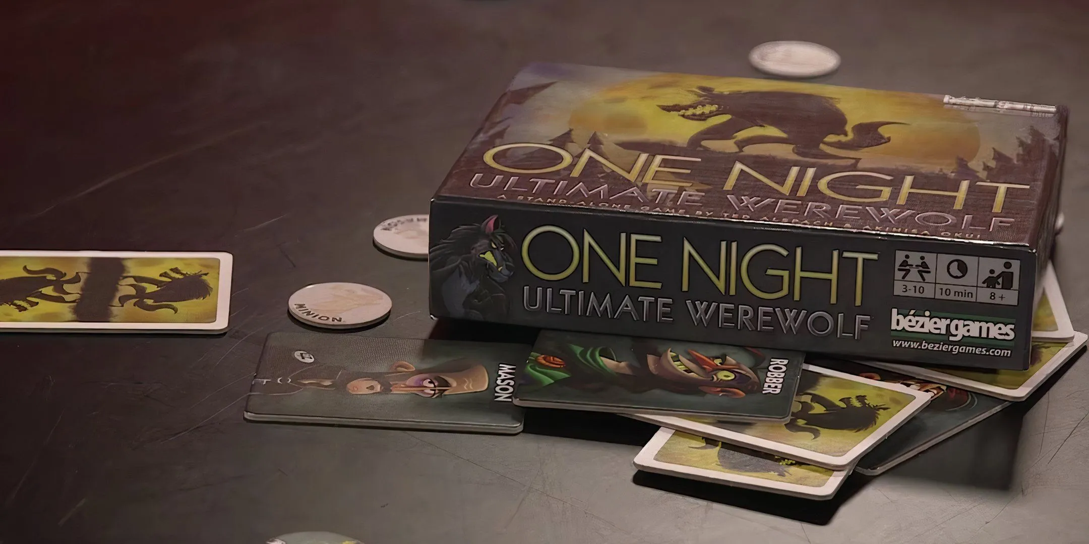 Cận cảnh các lá bài và logo game One Night Ultimate Werewolf trên bàn