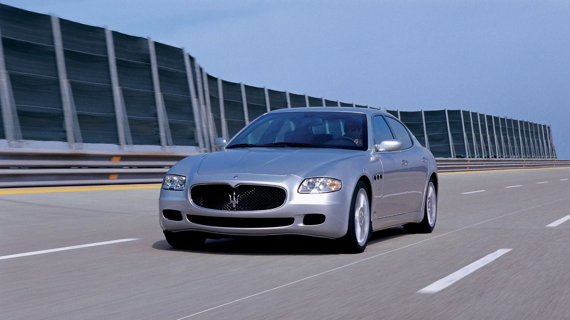 Ảnh 3/4 trước của Maserati Quattroporte V màu bạc (2003), nhấn mạnh kiểu dáng thể thao pha nét sang trọng.
